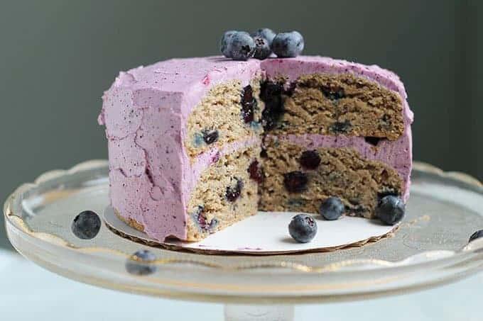 sliced first birthday cake with blueberries on stand